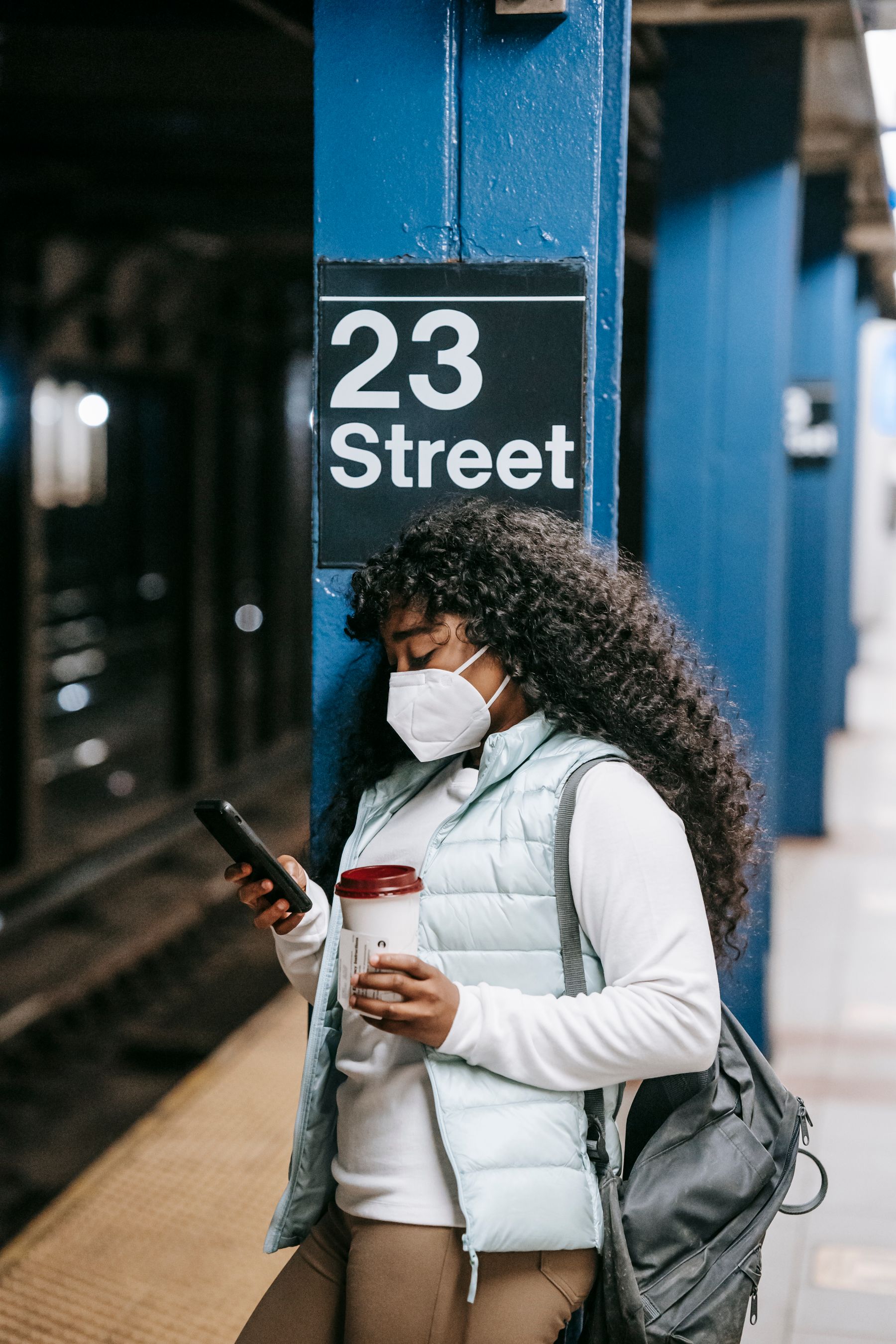 Black woman using a smartphone on a subway platform