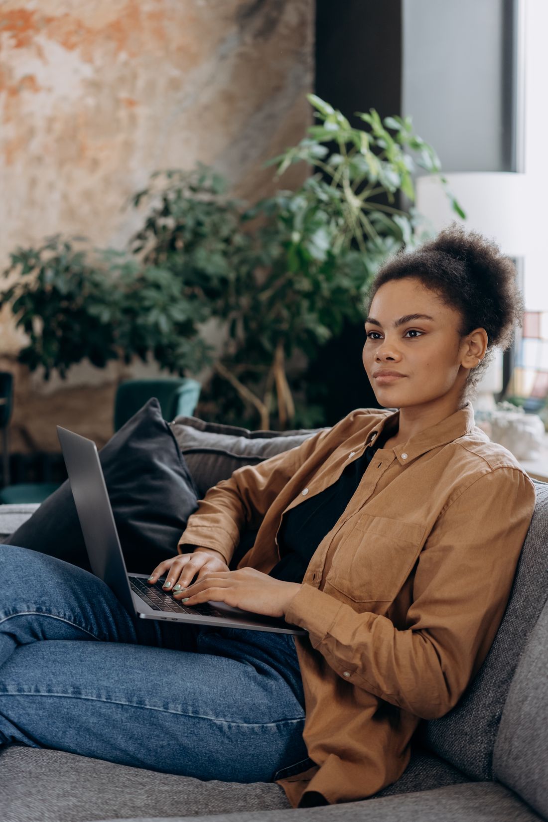 Black woman at home using a laptop on a sofa
